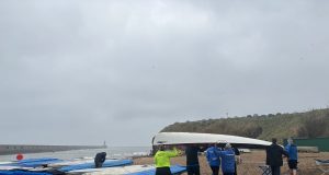 Tynemouth Rowing Club group of people carrying a white boat on the beach
